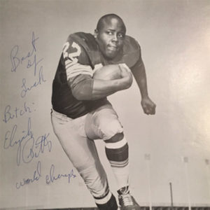 African-American man with football in uniform running on autographed picture