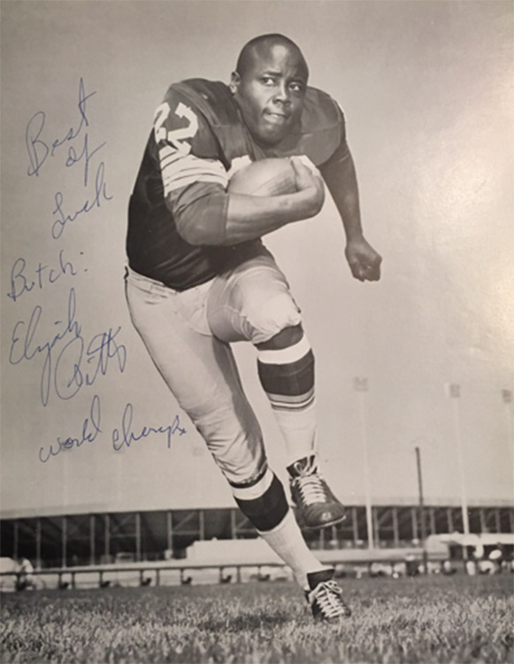 African-American man with football in uniform running on autographed picture