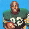African-American man in green and yellow football uniform holding a ball in his right hand with logo