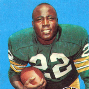 African-American man in green and yellow football uniform holding a ball in his right hand with logo