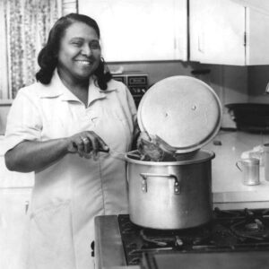 African-American woman cooking in kitchen with pot on stove