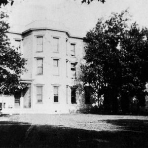 Three-story building with porch between two trees