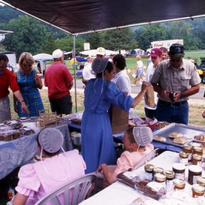 Group of white men and women buying and serving food in tents