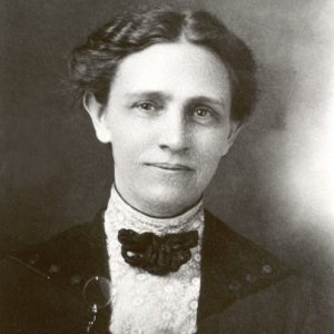 Portrait of white woman smiling with soft wavy hair lace blouse with ribbon and lapel monocle