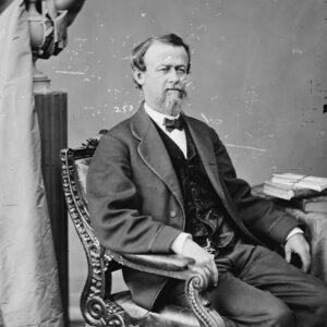 White man in suit seated in ornate chair