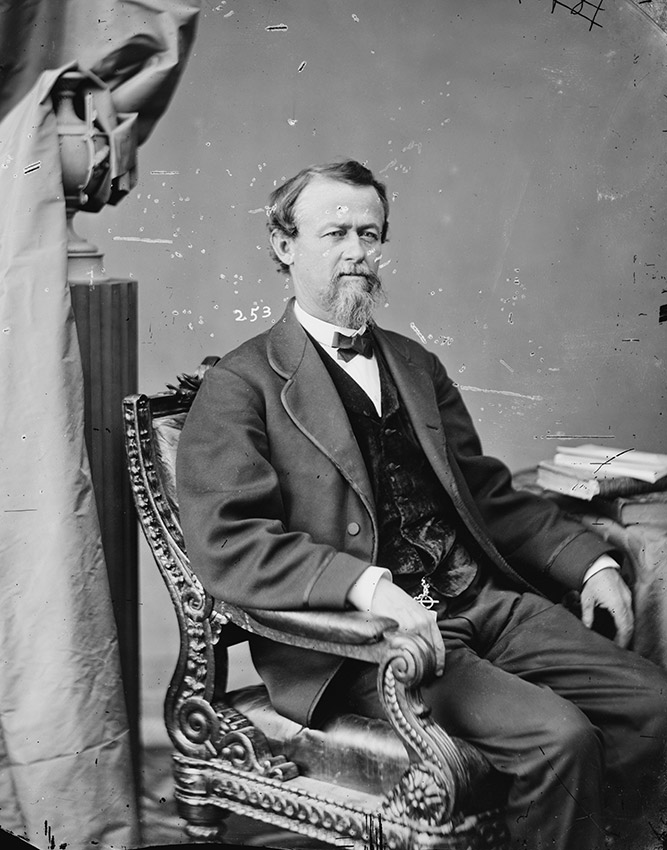 White man in suit seated in ornate chair
