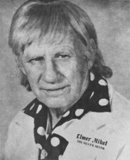 Older white man with long hair in "Elmer Mikel" shirt