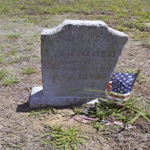 Weathered gravestone with small American flag in cemetery