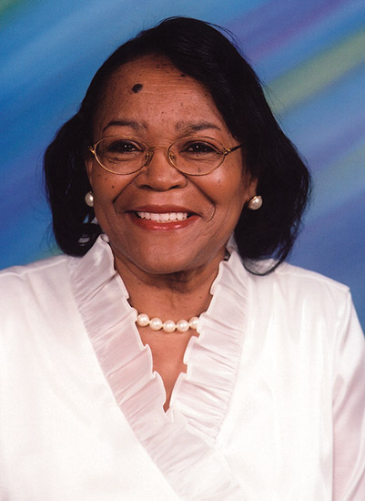 African-American woman with glasses smiling in white top