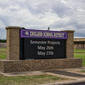 "England School District" electronic sign on brick base with columns on school campus