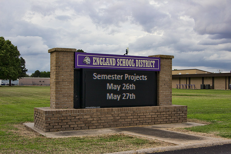 "England School District" electronic sign on brick base with columns on school campus