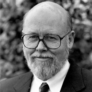 Bald white man with glasses and beard in suit and tie