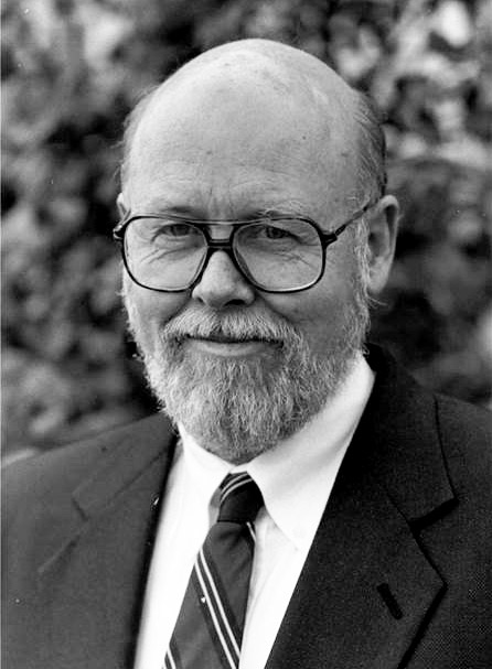 Bald white man with glasses and beard in suit and tie
