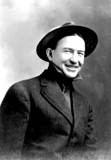 White man smiling in suit and hat
