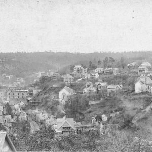 Aerial view of town buildings and houses with tree covered hills