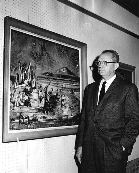 white man in suit looking at painting on wall