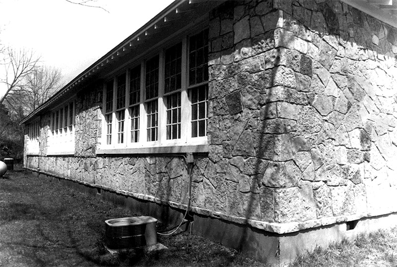 Side view of single-story stone building with multi-paned windows