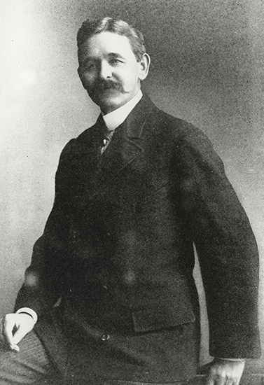 White man with mustache in suit and tie