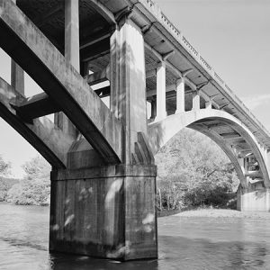 Underside of concrete bridge as seen from river below