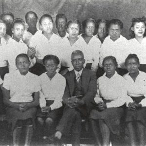 African-American girls in matching dresses sitting with African-American man in suit and tie