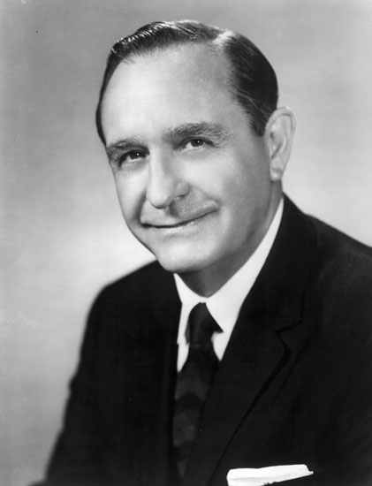 White man with dark hair posing in suit and tie