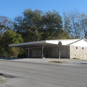 Single-story storefront with stone walls and covered entrance on two-lane highway