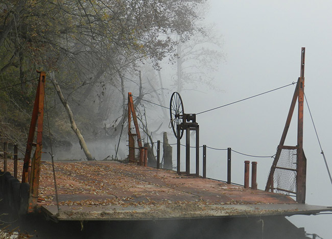 Empty ferry on foggy river bank