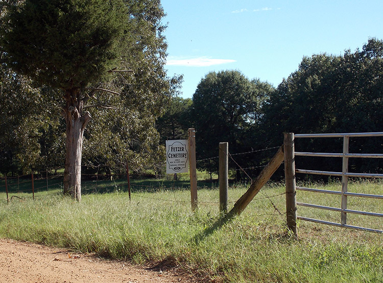 Metal gate with barbed wire fence and "Fetzer Cemetery" sign