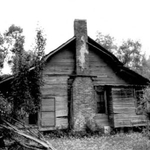 Side view of dilapidated single story house with brick chimney