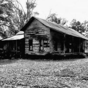Front view of dilapidated single-story house with covered porch