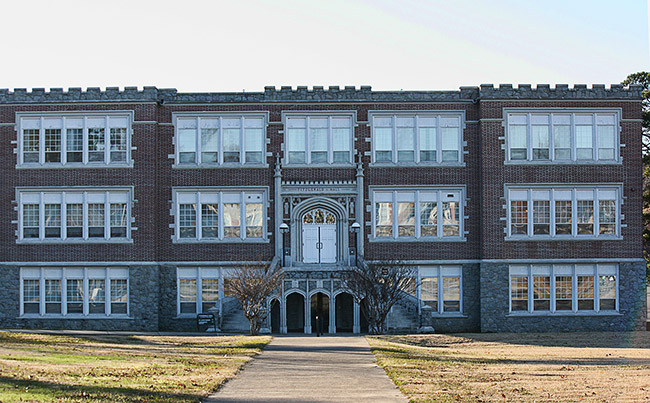 Three-story brick school building with arched entrance and stairs