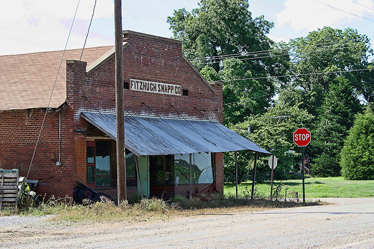Single-story brick storefront with wood awning and stop sign