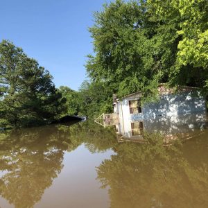 Single-story house and barn on flooded farm