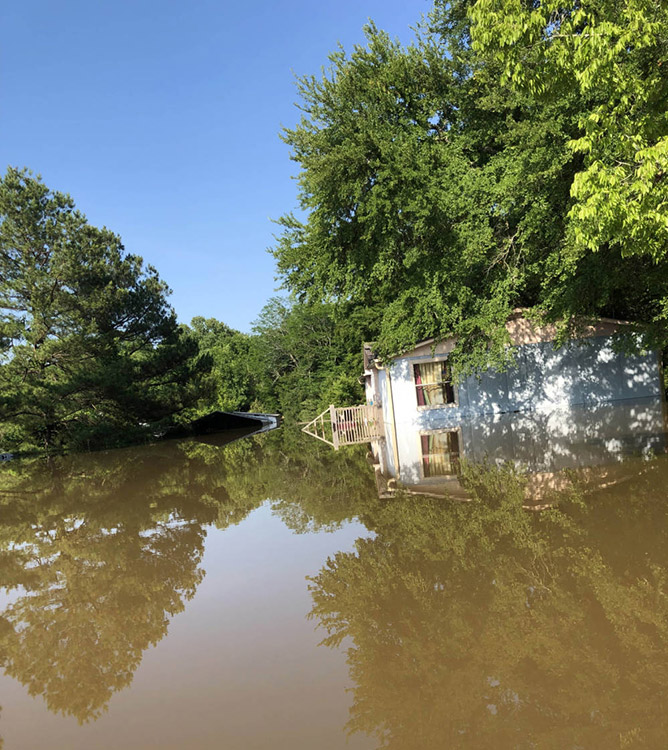 Single-story house and barn on flooded farm