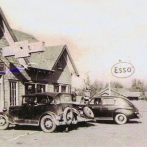 Brick building with signs including an "Esso" sign with parked cars in front
