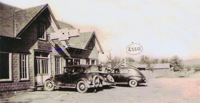 Brick building with signs including an "Esso" sign with parked cars in front