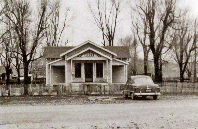 Single-story building on a dirt road with car parked in front