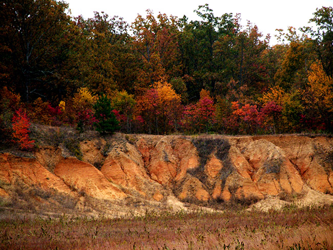 Ridge with fall foliage and exposed multicolored soil
