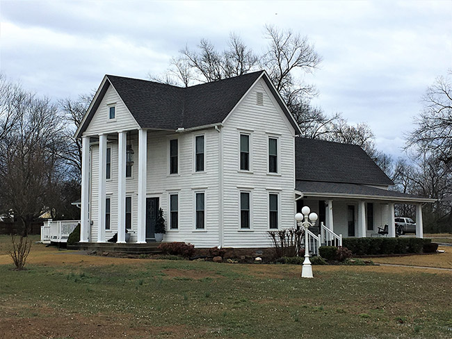Two-story house with four columns in front and covered side porch