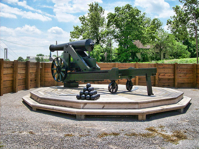 Cannon on platform with cannon balls and wooden retaining wall