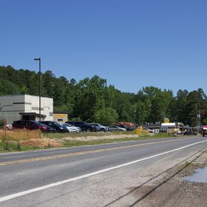 Multistory building with parking lot and restaurants on two-lane highway