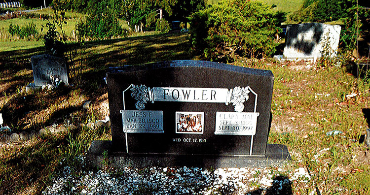 "Jess E. and Clara Mae Fowler" grave stone in cemetery with other gravestones in the background