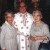 White man in white clerical robes with two older white women in dresses