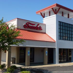 Exterior of "Franke's" restaurant with covered walkways and tower on parking lot