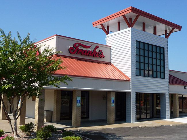 Exterior of "Franke's" restaurant with covered walkways and tower on parking lot
