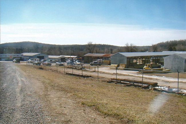 Warehouse buildings and metal storage buildings inside barbed wire fence next to gravel road