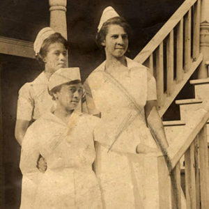 Three African-American nurses in uniform standing on staircase