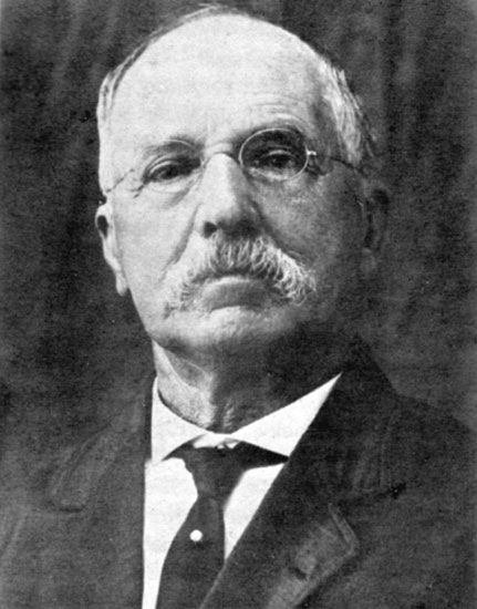 Old white man wearing glasses with mustache in suit and tie