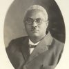 African-American man with white hair glasses and small mustache in suit