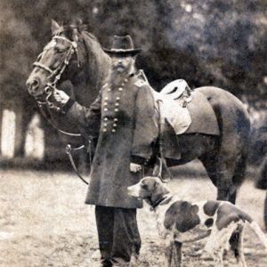 White man with long beard in military uniform with horse and dog
